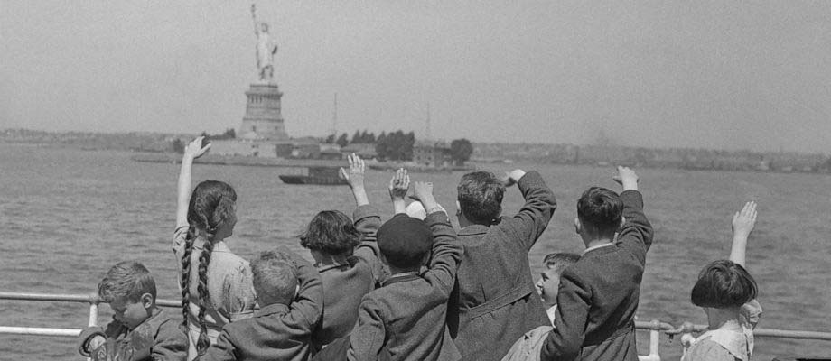 Immigrant children waving at the Statue of Liberty